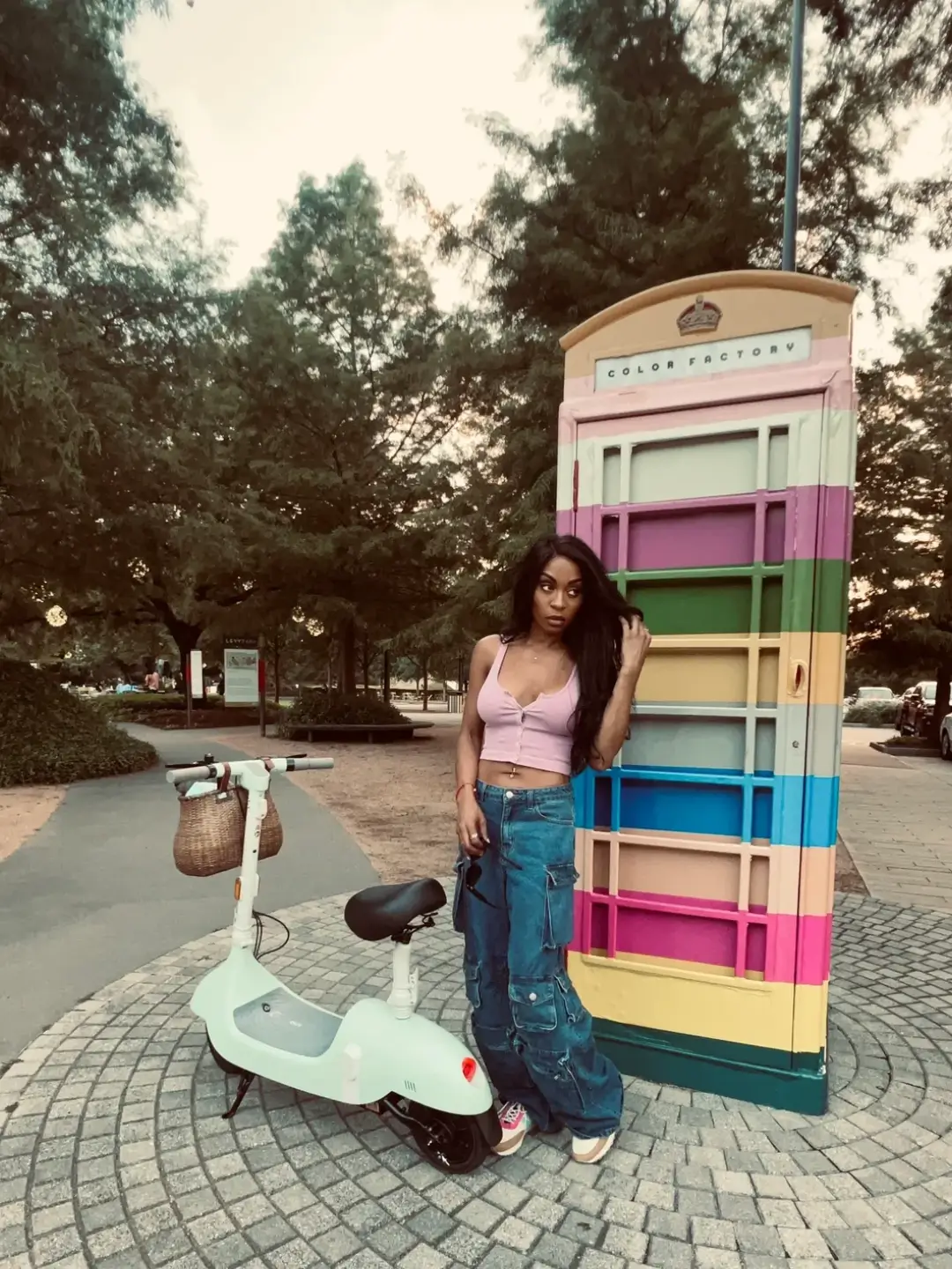 Woman with scooter by colorful phone booth.